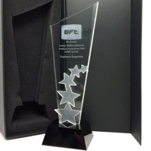 trophée en verre reprenant la forme d'un cornet tronqué, avec un socle en plastique trapézoïdal à la base rectangulaire.
